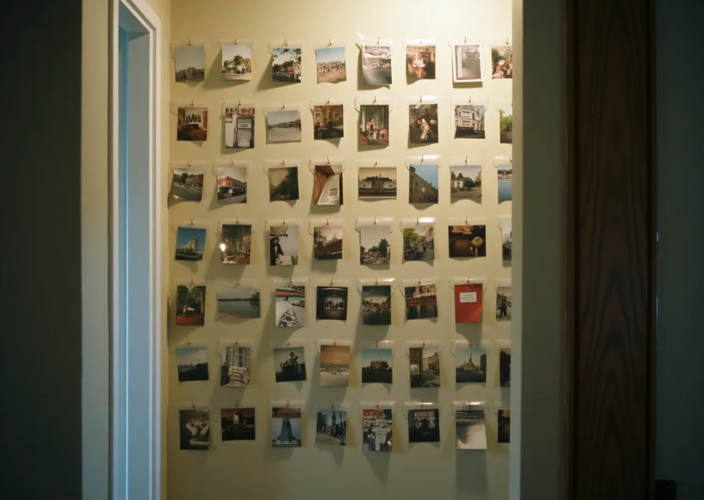 Rows of small unframed black-and-white photographs of the same kind of structure, each shot from the same distance and angle, pinned in a tight grid on a wall.